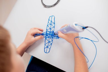 3D yazdırma kalemi olan odaklanmış çocuk oyuncak yaratıyor