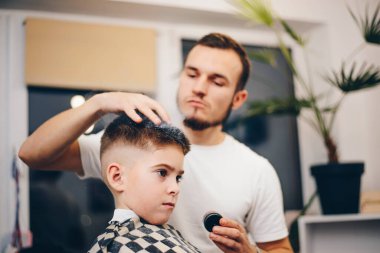 Berber kuaförde küçük şirin bir çocuğu tımar ediyor.