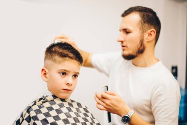 Berber kuaförde küçük şirin bir çocuğu tımar ediyor.