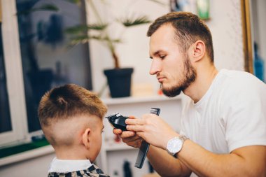 Berber kuaförde küçük şirin bir çocuğu tımar ediyor.