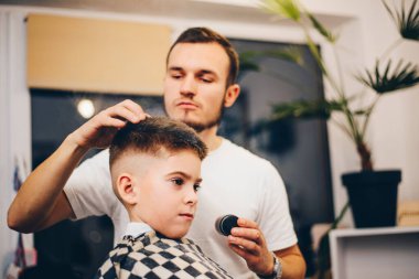 Berber kuaförde küçük şirin bir çocuğu tımar ediyor.