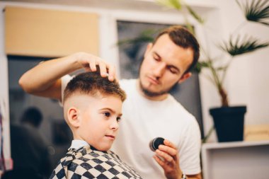 Berber kuaförde küçük şirin bir çocuğu tımar ediyor.