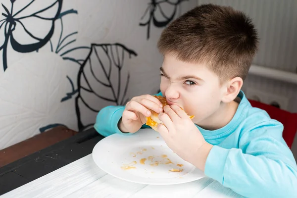 little boy eating food at the table