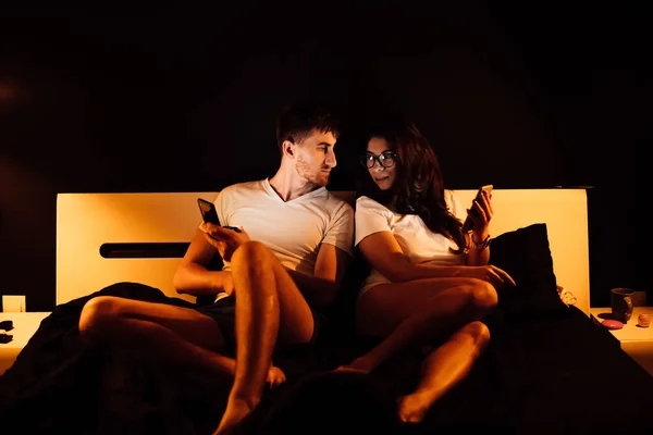 Pareja Joven Con Teléfonos Inteligentes Cama Por Noche — Foto de Stock