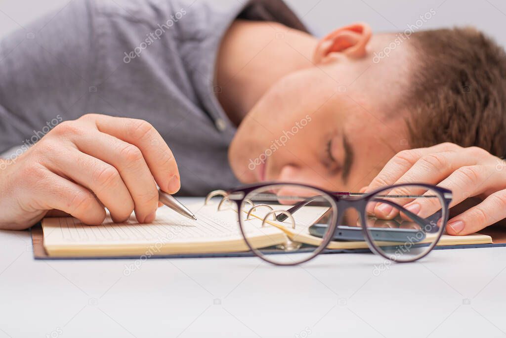 close up image of man sleeping on notebook.