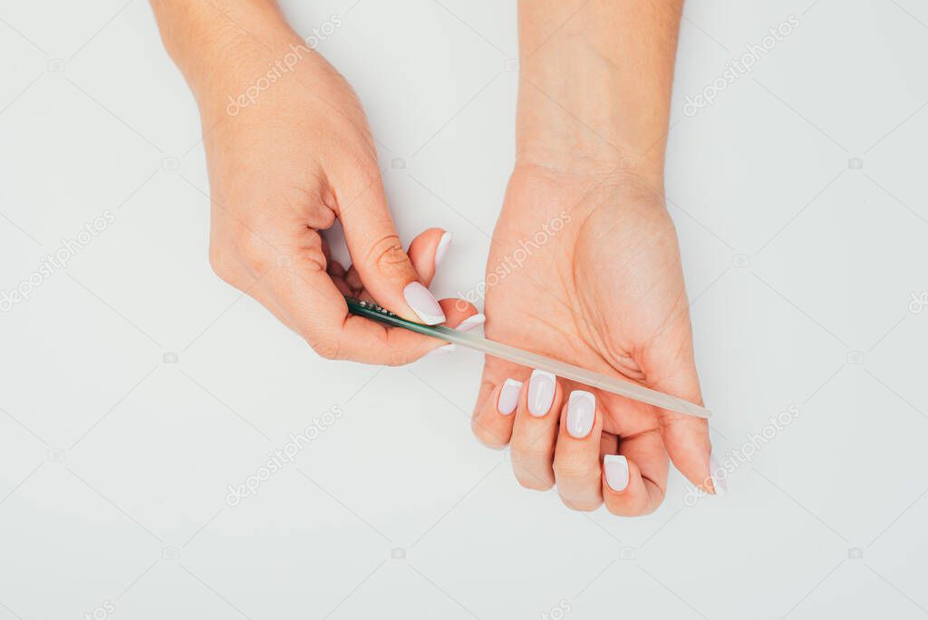 Hand filing nails with glass nail file on  background