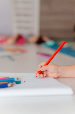 Yaratıcılığı ve sanatsal becerileri teşvik eden renkli işaretleri kullanarak kağıda neşeyle çizen küçük bir çocuk.