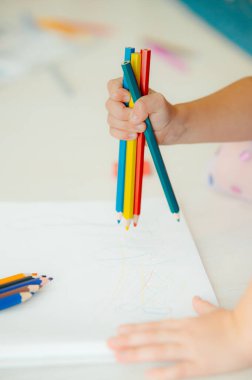 Bir çocuk, yaratıcı ve sanatsal ifade dünyasına tamamen hazır canlı renkli kalemleri hevesle tutar.