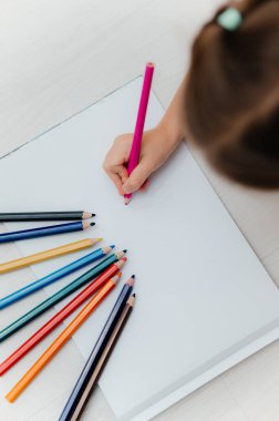 Beyaz kağıt üzerine renkli kalemler çizen bir çocuğun tepeden tırnağa fotoğrafı yaratıcı, eğitici, okula dönüş konsepti..