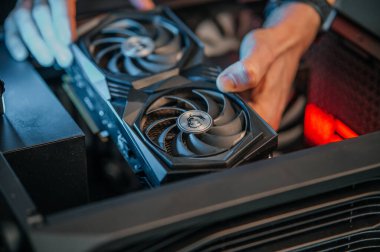 Ana karta bir video kartı yüklüyorum. Teknisyen bilgisayar parçalarını açık bir bilgisayar çantasına yerleştiriyor. PC montaj ve modernizasyon.