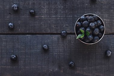 Tahta kasede taze toplanmış yabanmersini. Kırsal masada yeşil yapraklı sulu ve taze yaban mersini. Ahşap arka planda Bilberry. Merkez. Sağlıklı yeme ve beslenme kavramı