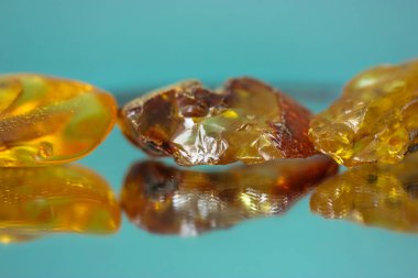 Ayna yüzeyinde doğal bir kehribar parçası, sarı yarı değerli bir taşın yansıması.