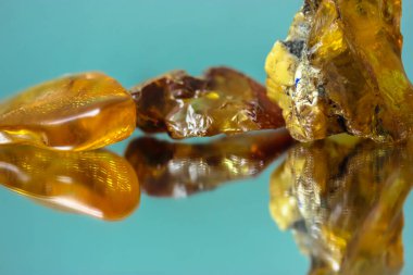 Ayna yüzeyinde doğal bir kehribar parçası, sarı yarı değerli bir taşın yansıması.