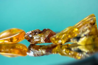 Ayna yüzeyinde doğal bir kehribar parçası, sarı yarı değerli bir taşın yansıması.