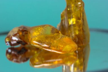 Ayna yüzeyinde doğal bir kehribar parçası, sarı yarı değerli bir taşın yansıması.