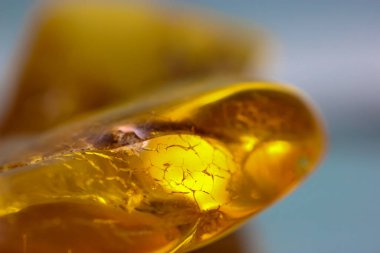 Ayna yüzeyinde doğal bir kehribar parçası, sarı yarı değerli bir taşın yansıması.