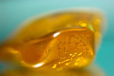 Ayna yüzeyinde doğal bir kehribar parçası, sarı yarı değerli bir taşın yansıması.