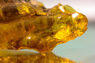 Ayna yüzeyinde doğal bir kehribar parçası, sarı yarı değerli bir taşın yansıması.