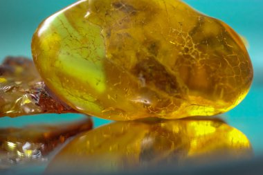 Ayna yüzeyinde doğal bir kehribar parçası, sarı yarı değerli bir taşın yansıması.