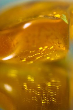 Ayna yüzeyinde doğal bir kehribar parçası, sarı yarı değerli bir taşın yansıması.