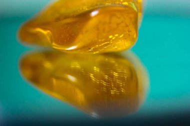 Ayna yüzeyinde doğal bir kehribar parçası, sarı yarı değerli bir taşın yansıması.