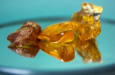 Ayna yüzeyinde doğal bir kehribar parçası, sarı yarı değerli bir taşın yansıması.