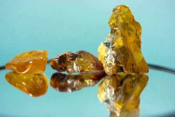 A piece of natural amber on a mirror surface, a reflection of a yellow semi-precious stone