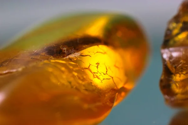 A piece of natural amber on a mirror surface, a reflection of a yellow semi-precious stone