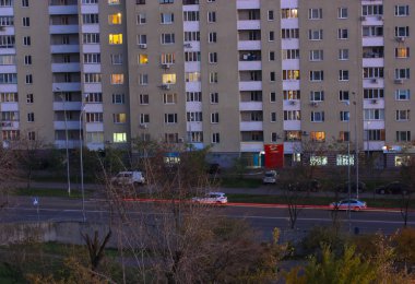 Akşamları şehir caddesinde hızlı trafik ve kırmızı farlar bulanık, yatak odası bölgesinde çok katlı evler ön cephede. Kiev, Ukrayna