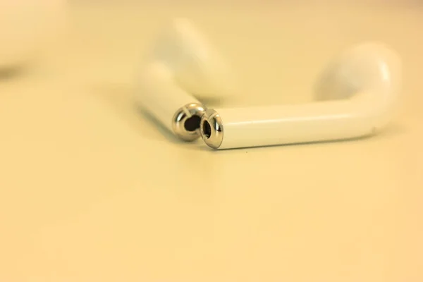 Fones de ouvido airpods brancos em uma mesa branca, um dispositivo para ouvir música — Fotografia de Stock