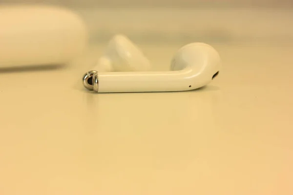 White airpods headphones on a white table, a device for listening to music — Stock Photo, Image