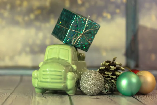Carro de brinquedo com uma árvore de Natal e uma caixa de presentes no telhado contra a janela — Fotografia de Stock