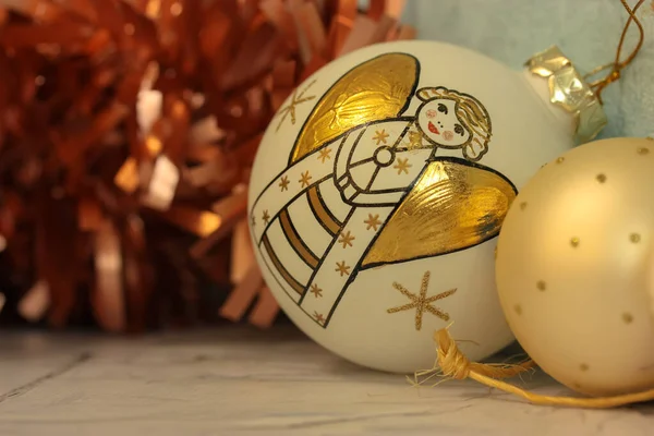 Parlayan ışıkların arasında altın bir melek olan beyaz Noel ağacı topu. Yapay kırmızı kabarık çelenk. — Stok fotoğraf