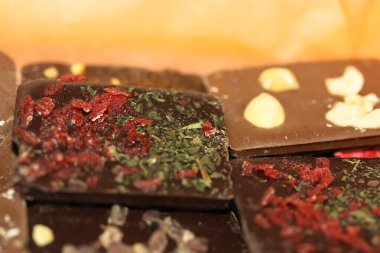 Turuncu kraft kağıdına izole edilmiş fındıklı, otlu ve çiçekli el yapımı süt ve koyu çikolata. Kimse yok.