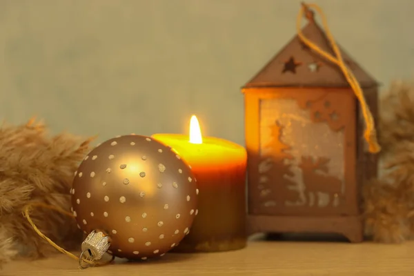 New Years decor: burning candle, decorative reindeer lantern, close-up Christmas tree toy, warm festive background