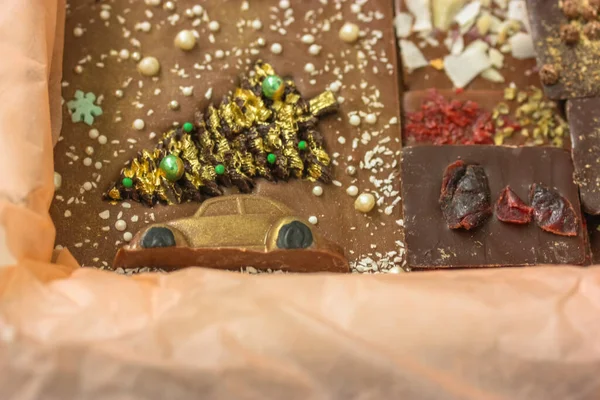 Barres de lait et de chocolat noir faites à la main isolées dans du papier kraft orange, image d'une voiture avec un arbre de Noël sur le toit. Pas de peuple — Photo