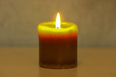 Ahşap bir yüzey üzerinde yanan sarı mum. İç kısımdaki mavi duvara yakın plan. Minimalizm ve insan yok.