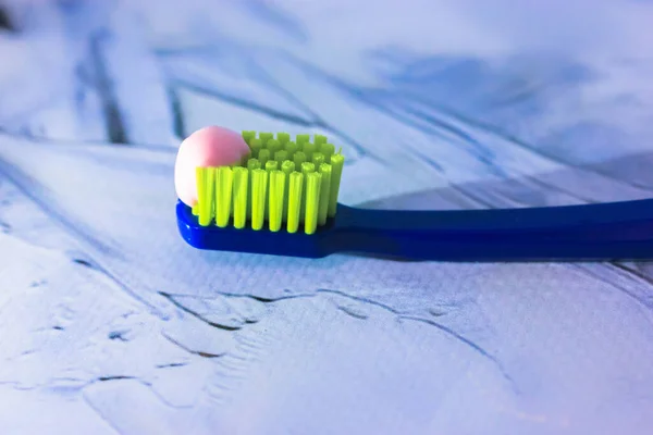 Escova de dentes azul com cerdas verdes close-up, pasta de dentes rosa. Produtos de higiene e cuidados dentários do dentista — Fotografia de Stock