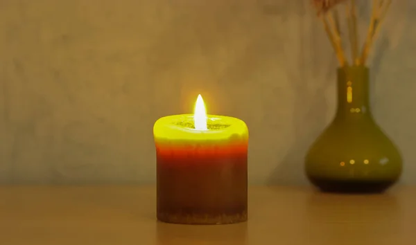 Una vela encendida en la semi-oscuridad y un pequeño jarrón verde en el fondo. Interior moderno, el ambiente de las vacaciones de Año Nuevo —  Fotos de Stock