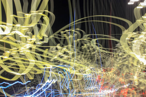 Chaotic abstract yellow lines of lights from car headlights driving fast through the city at night. A long exposure