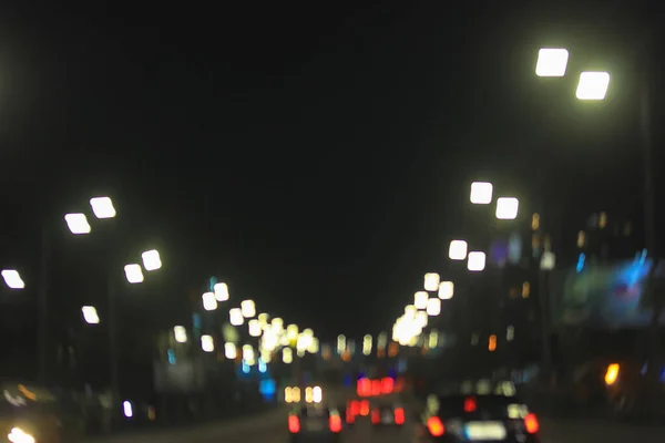Автомобили на дороге в городе поздно ночью и огни фар, неоновые огни, рекламные вывески и уличные фонари. Вечерние пробки в большом городе — стоковое фото