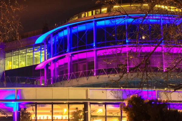 Dairesel bina, panoramik pencerelerde sıcak bir parıltı olan leylak ve mavi neon ışıklarla neşeli bir şekilde aydınlatılıyor. İnsan yok. Kiev, Ukrayna 'da Noel' den ve yeni yıldan önce.