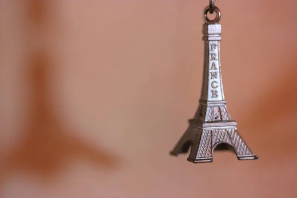 Schlüsselanhänger aus Metall in Form des Eiffelturms in Paris, Frankreich. Souvenir von der Reise in Nahaufnahme auf orangefarbenem Hintergrund — Stockfoto