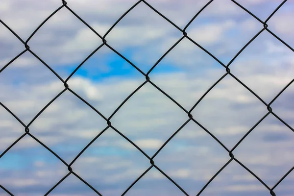 금속 보호 격자 또는 흰 구름이 있는 푸른 하늘을 배경으로 한 그물. 보호 시설, 주차장 혹은 감옥 — 스톡 사진