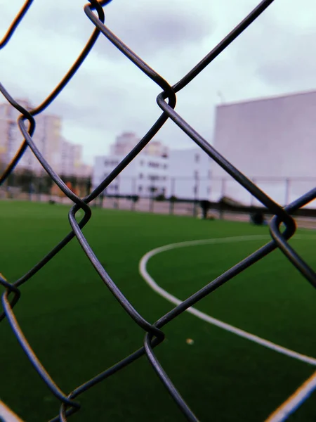 Red de seguridad metálica primer plano de un campo de fútbol, un juego de deportes al aire libre y jugadores de fútbol —  Fotos de Stock