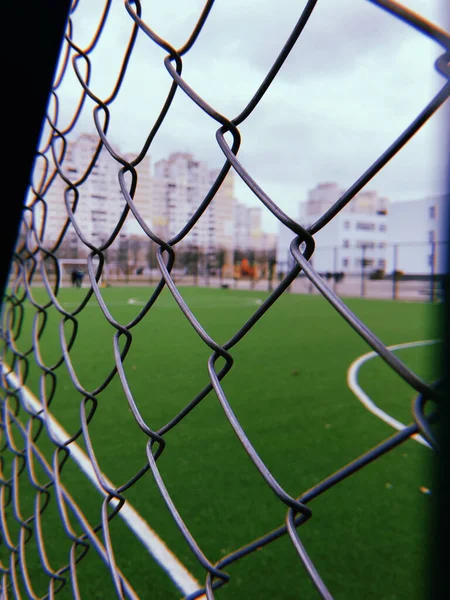 Red de seguridad metálica primer plano de un campo de fútbol, un juego de deportes al aire libre y jugadores de fútbol — Foto de Stock