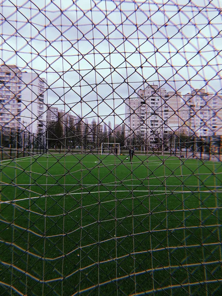 Red de seguridad metálica primer plano de un campo de fútbol, un juego de deportes al aire libre y jugadores de fútbol — Foto de Stock