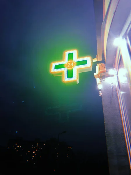 Logga in i form av ett kors i ett 24-timmars apotek lyser mot natthimlen — Stockfoto