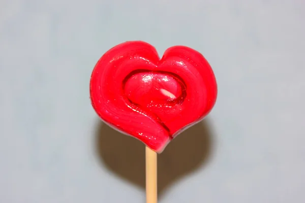 Lollipop op een stok in de vorm van een rood hart, een traktatie voor Valentijnsdag — Stockfoto