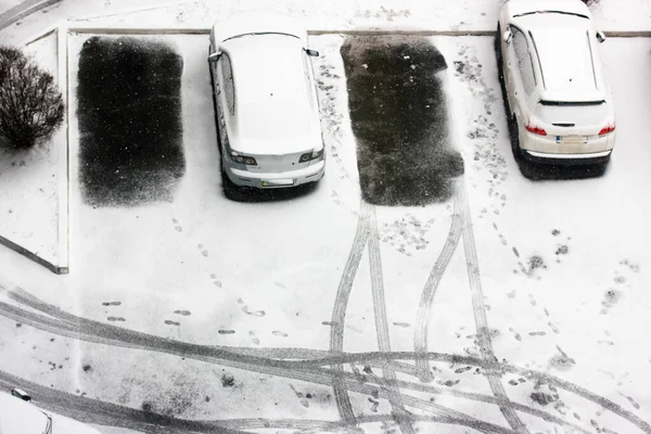 Cars covered with snow in the parking lot in winter, free parking space and tire tracks. View from above — Stock Photo, Image